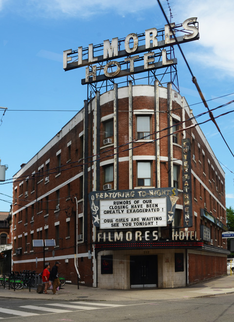 front of Filmores Hotel on Dundas Ave., with sign over front entrance that says the rumours of our closing are greatly exaggerated
