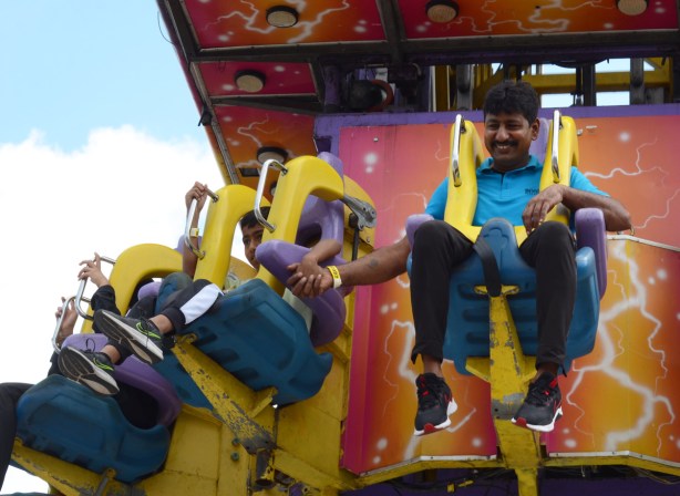 two men holding hands as they get ready for a free fall ride at the ex