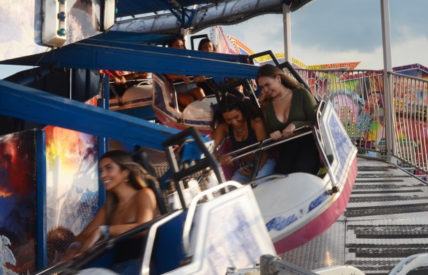 young women laughing as they go around in circles on a ride at the cne midway
