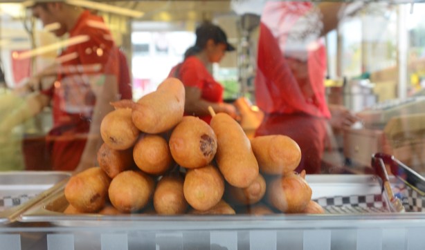 looking through a window, a pile of corndogs for sale at the ex