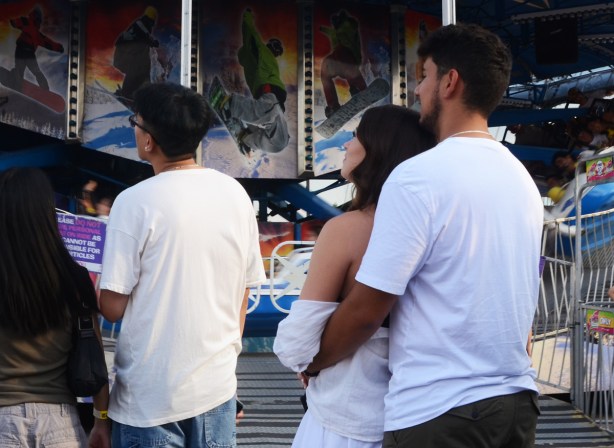a young man has his arms around the waist of a woman as they watch at the cne