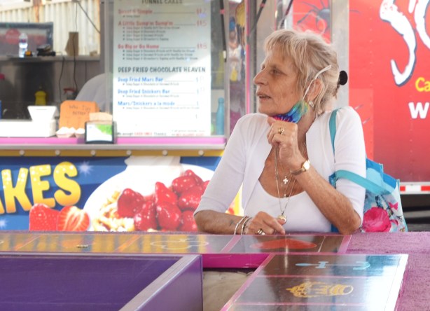 an older woman sitting at a crown and anchor betting game at the ex