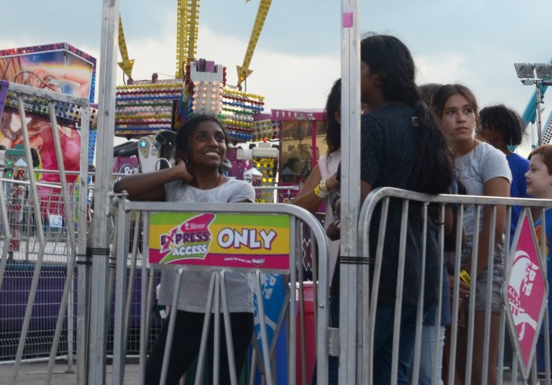 a young woman waits her turn for a cne midway ride
