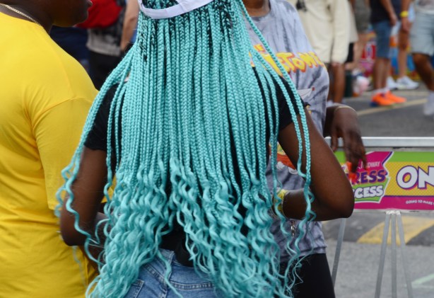 back of a woman in a white baseball cap and very long turquoise dreadlocks, braids