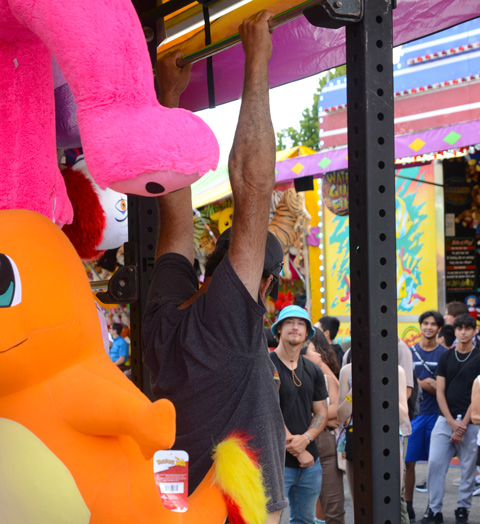 people watching a man hang from a bar