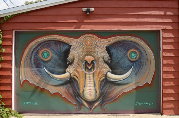 a street art mural on a garage door, rust coloured wood garage. Image looks like an elephant