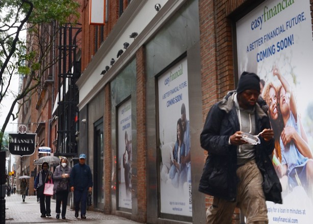 a man is eating as he walks past ads for a bank and financial security, Massey Hall sign in the background