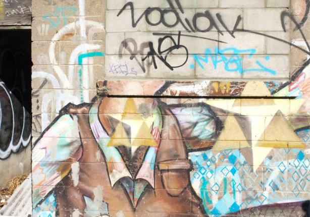 part of an od mural, faded, headless man with brown vest, blue diamond motifs