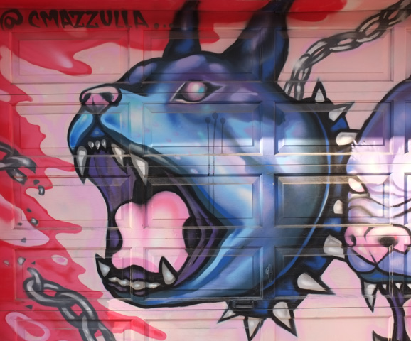 street art on garage door, large dogs with spiked collars, big teeth, open mouth, pink tongues, painted by C mazzulla