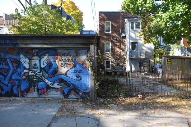 alley view, mural on a garage door, back of three storey house, back yard