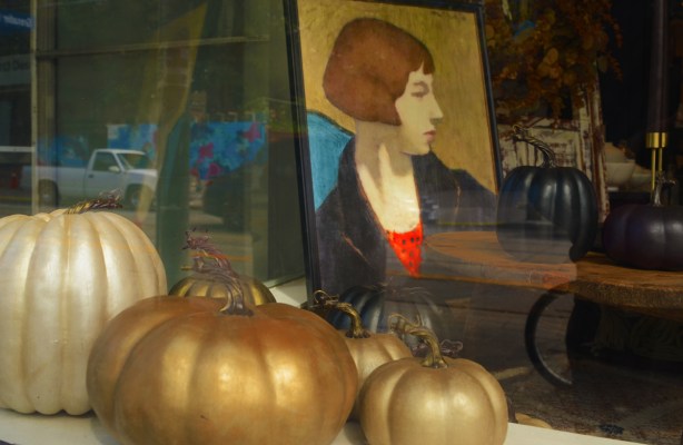 view in a store window, gold and black and white pumpkins, picture of a woman in a frame