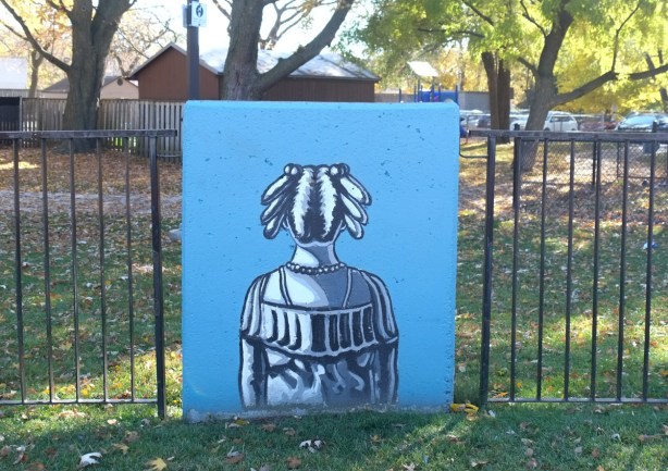 concrete block against a metal fence with simple painting of a person's back