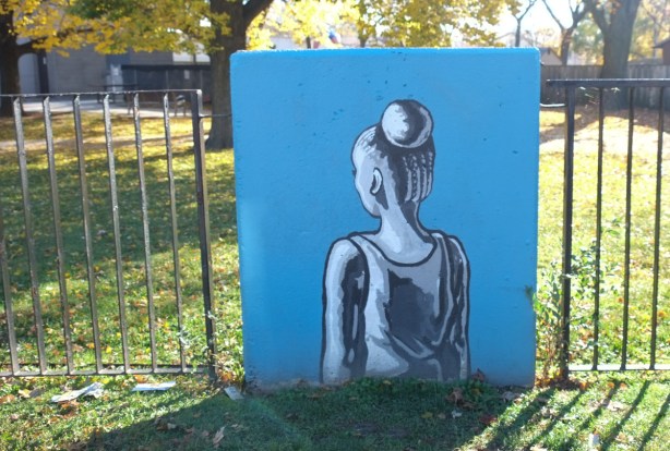 concrete block against a metal fence with simple painting of a person