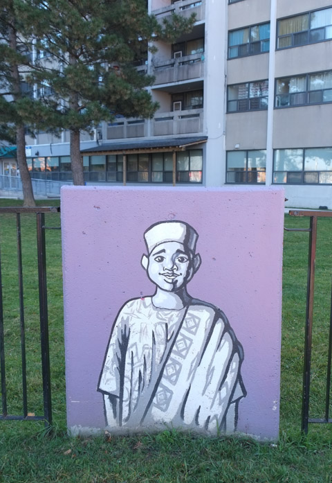 concrete block against a metal fence with simple painting of a person, male, african type clothing including hat