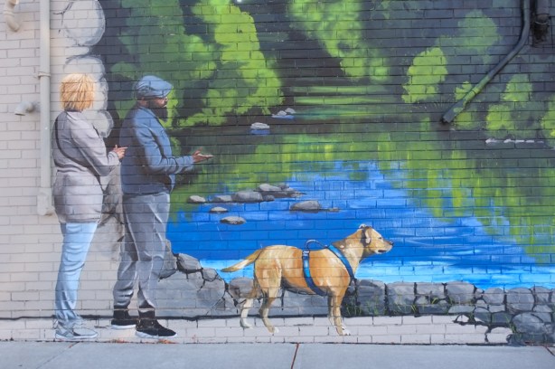 part of a mural, a couple walking their dog beside a creek, with trees