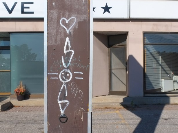 on a metal pole, a small painted white heart and three letters, S O and S.