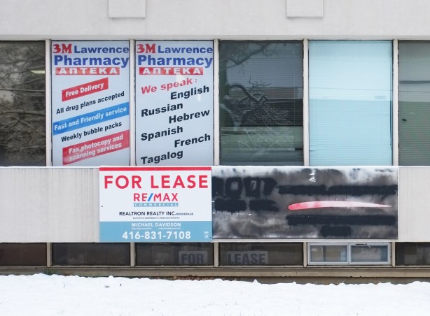 windows of an old medical building, empty, for lease sign on it, signs in window say we speak many languages, english, hebrew, russian, spanish, french, tagalog
