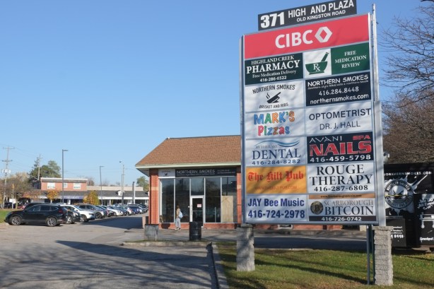 sign in a strip mall in Highland Creek, listing and advertising the businesses there such as CIBC, Scarborough Bitcoin, a pharmacy, By the Lake Dental, The Kilt Pub,