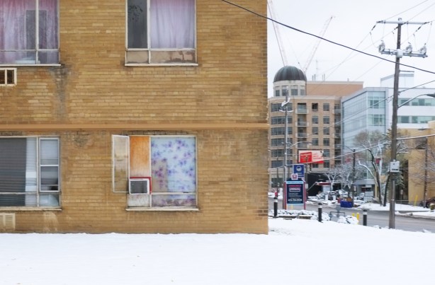 lower corner of a brown brick apartment building with Bathurst St street scene in the background