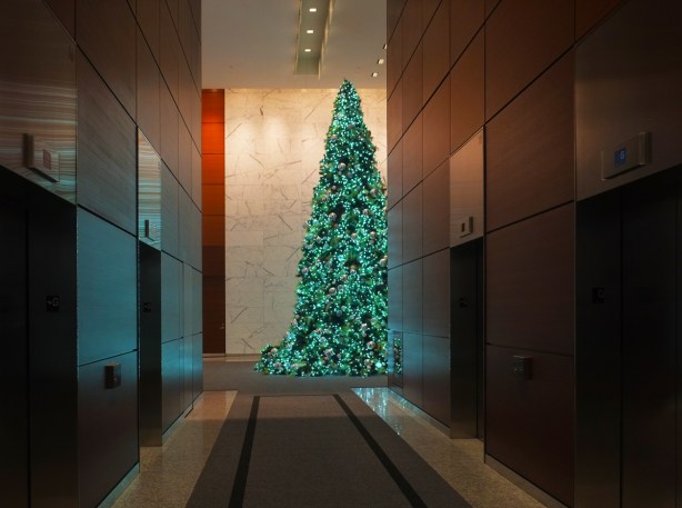 a large christmas tree in office building, partially obscured by a bank of elevators 