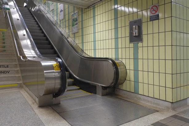 escalator from platform level at osgoode ttc subway station, yellow and green tiles on the walls