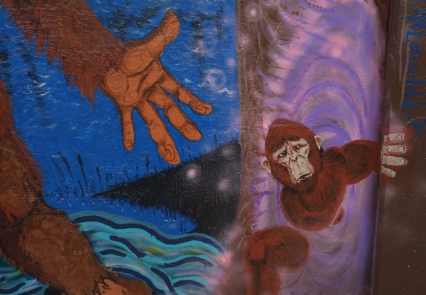 close up of part of a mural with large monkey or ape hand reaching for a smaller monkey or ape