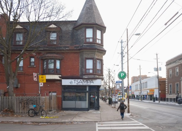 Tsampa Tibetan restaurant with a turret on its roof, on the corner of Queen Street West, a pedestrian walking past