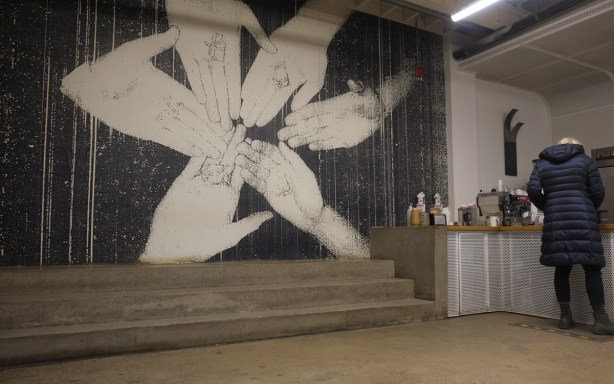 large black and white painting of 6 hands coming together, radial symmetry, on wall of Sam James Coffee Bar