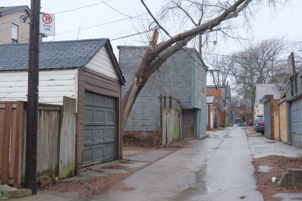 alley behind Gerrard St., large old garage, leaning, covered with grey shingles, old tree