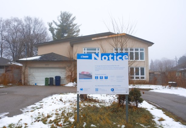 blue and white development notice for Behar planning and design co to redevelopment a section of land on Bayview Ave that involves demolishing a few houses, including two storey beige house still there, sign in the front yards.