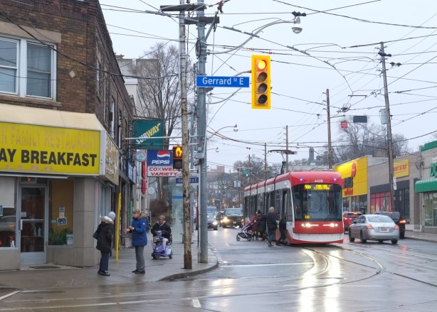 TTC streetcar southbound on Coxwell, stopped at Gerrard where people are getting on and off 