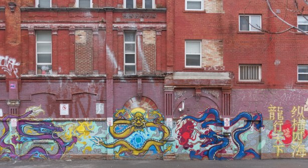 on the side of a large old brick buildig, a long horizontal mural of dragons, in chinatown, 