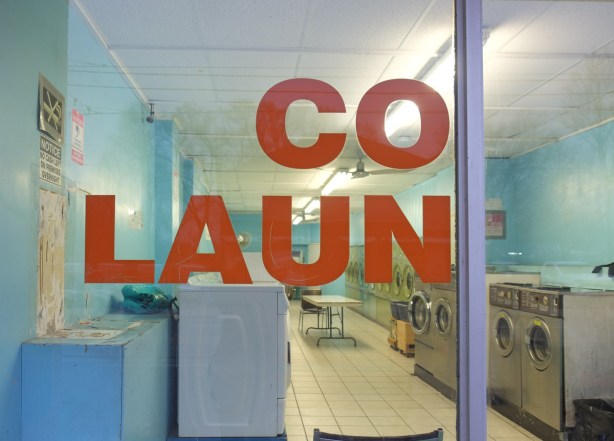 looking in the window of a laundromat, sign on window says co laun