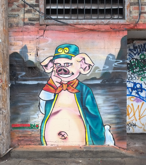 pig standing upright with green jacket and red necktie, green cap, jacket open in front to reveal fat tummy and belly button
