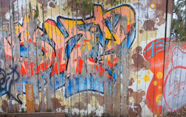 peeling street art on a wood fence in an alley