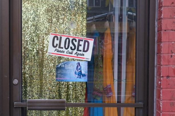 closed sign on a shop door, with a glittery gold curtain partially covering the window of the door 