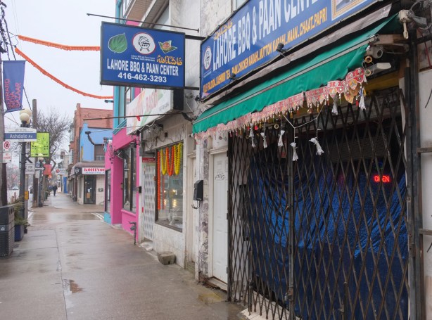 Gerrard street sidewalk scene, with Lahore BBQ and paan center in the foreground, other stores