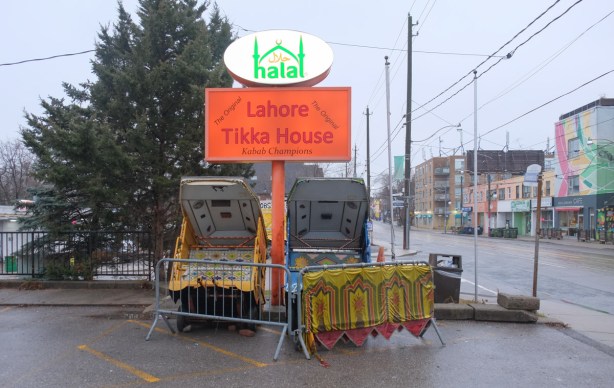 Outside the Lahore Tikka House restaurant, two tictoks sit behind barricades, in an otherwise empty parking lot