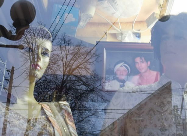 photographs and mannequins on display in a window, reflections of street scene in the window too
