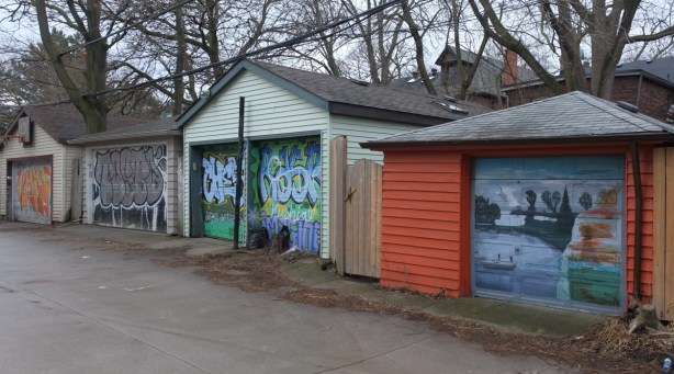 garages in an alley behind Danforth with doors with old paintings on them 
