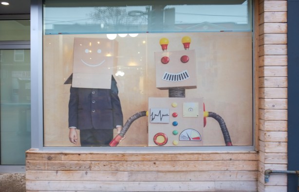 two cardboard robots, male and female, in a window