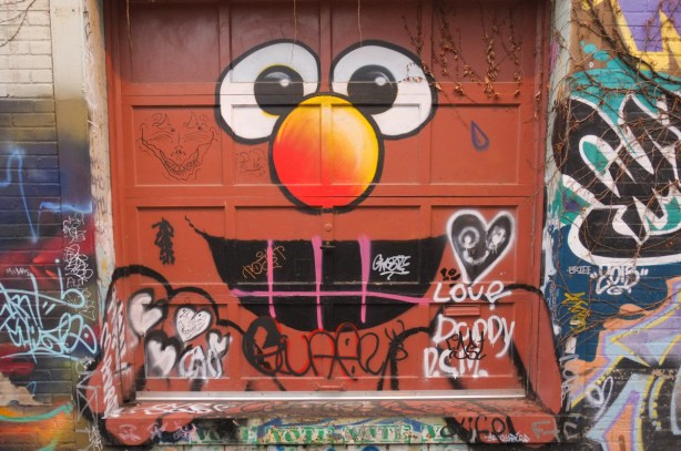 Elmo painted on a square garage door in an alley