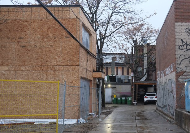 plywood covers a new building, infill housing being constructed in an alley, 