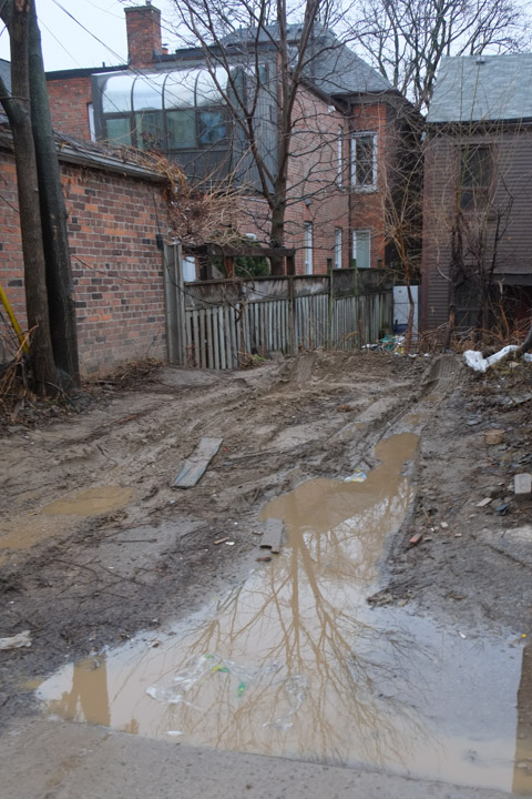 backyard on a laneway that is all mud and puddles