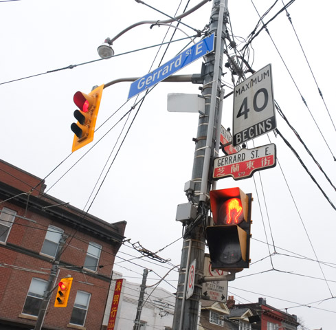 traffic signal, red light, on pole with many street signs, plus 40 kmh sign, Broadview and Gerrard