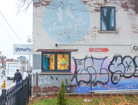 side of a building, window, with interior lights on, illuminated sign of a cup of tea in the window, Lamoon Cafe, Thai drinks and food 