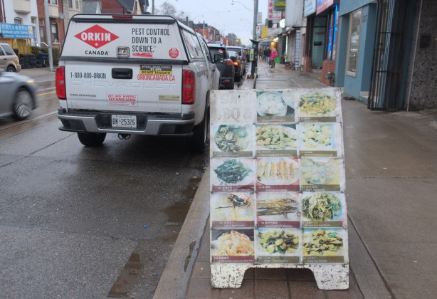 faded menu board on the sidewalk, chinese restuarant, also a van from orkin pest control parked there 