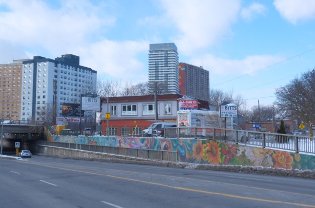 wall beside sidewalk at railway underpass, mural by Alex Bacon and Que Rock 