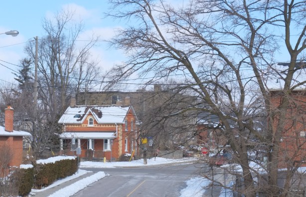 old brick house, with lowrise apartment building behind it