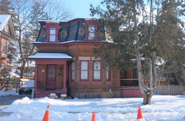 older brick house with slate roof, trim is painted a dark pink colour